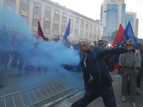 A protester throws a smoke flare during an anti-government rally in Tirana, Saturday, May 11, 2019. Protesters demand the Socialist government to resign and call an early parliamentary election.