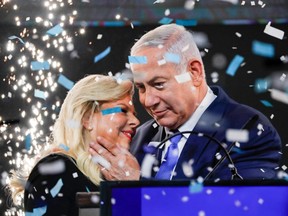 Israeli Prime Minister Benjamin Netanyahu embraces his wife Sara as confetti and fireworks are blown during his appearance before supporters at his Likud Party headquarters in the Israeli coastal city of Tel Aviv on election night early on April 10, 2019.