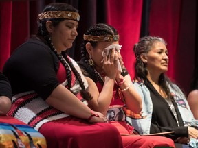 Lorelei Williams, centre, whose cousin Tanya Holyk was murdered by serial killer Robert Pickton and aunt Belinda Williams went missing in 1978, wipes away tears while seated with Rhiannon Bennett, left, and Sophie Merasty, right, after responding to the report on the National Inquiry into Missing and Murdered Indigenous Women and Girls, along with other Indigenous women and allies in Vancouver, on June 3, 2019.