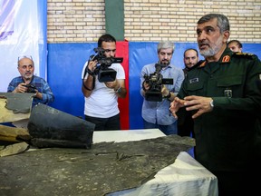 General Amir Ali Hajizadeh (right), Iran's Head of the Revolutionary Guard's aerospace division, speaks to media next to debris from a downed U.S. drone reportedly recovered within Iran's territorial waters and put on display by the Revolutionary Guard in the capital Tehran.