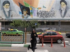 An Iranian woman walks past a mural painting depicting the late founder of the Islamic Revolution Ayatollah Ruhollah Khomeini (R) and  Iran's supreme leader Ayatollah Ali Khamenei in the Iranian capital Tehran on June 25, 2019.