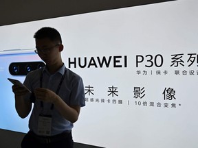A man looks at his smartphone at a Huawei stand during the Mobile World Congress at the Shanghai New International Expo Centre on June 26, 2019.