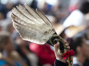 A red ribbon attached to an eagle feather is held up during ceremonies marking the release of the Missing and Murdered Indigenous Women report in Gatineau, Monday June 3, 2019.