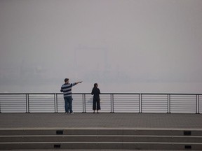 A man and woman look out at the harbour as smoke from wildfires burning in the province fills the air, in Vancouver on August 20, 2018. The federation of more than 21 municipalities in Greater Vancouver warns the roughly 2.5-million residents across the region to expect air quality advisories in the coming months. Officials with Metro Vancouver issued the warning Tuesday, advising those with breathing problems to brace for a smoky summer, although they say it is difficult to predict if 2019 will be worse than the last two years.