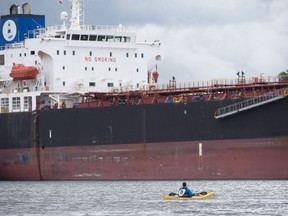 Kinder Morgan protester Jake Hubley looks on from his kayak as an oil tanker is guided by tugs into the Kinder Morgan facility in Burrard Inlet in Burnaby, B.C., Wednesday, May 9, 2018. Legislation barring oil tankers from loading at ports on the northern coast of British Columbia slipped over its final hurdle in the Senate on Thursday, despite last-minute attempts by Conservative senators to convince their colleagues to kill it.