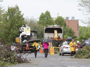 Residents survey the damage as debris downed tress are piled on the street as cleanup begins, the day after a tornado touched down in the Ottawa suburb of Orleans, Ont., on Monday, June, 3, 2019.
