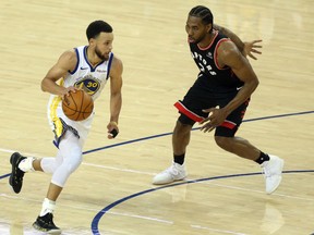 Golden State Warriors guard Stephen Curry (30) moves the ball past Toronto Raptors forward Kawhi Leonard (2) during the third quarter in game three of the 2019 NBA Finals at Oracle Arena.