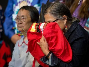 An Indigenous woman embraces the final copy of the National Inquiry into Missing and Murdered Indigenous Women and Girls at a ceremony marking the conclusion of the inquiry at the Museum of History in Gatineau, Que., on June 3, 2019.