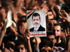 A picture of Egypt’s first Islamist President Mohamed Mursi is held up as supporters cheer during a rally at Tahrir Square in Cairo July 13, 2012.