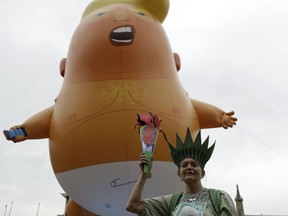 A woman posing as statue of liberty stands next to the 'Trump Baby' blimp as people gather to demonstrate against the state visit of President Donald Trump in Parliament Square, central London, Tuesday, June 4, 2019. Trump will turn from pageantry to policy Tuesday as he joins British Prime Minister Theresa May for a day of talks likely to highlight fresh uncertainty in the allies' storied relationship.