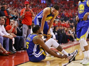 Klay Thompson #11 of the Golden State Warriors helps Kevin Durant #35 to his feet in the first half against the Toronto Raptors during Game Five of the 2019 NBA Finals at Scotiabank Arena on June 10, 2019 in Toronto, Canada. Fans cheered Durant's departure while others expressed concern.
