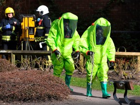 In this file photo taken on March 08, 2018 members of the fire brigade in green biohazard encapsulated suits work to re-attach the tent at the scene of a nerve agent attack at The Maltings shopping centre in Salisbury, southern England.