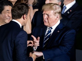 U.S. President Donald Trump, right, speaks to French President Emmanuel Macron while Japanese Prime Minister Shinzo Abe listens, at the G20 Summit in Osaka on June 28, 2019.