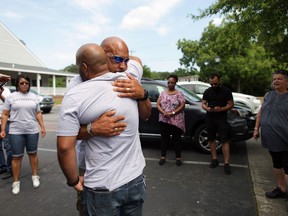 Chris Mitchell, Sr., facing camera, hugs his son, Chris Mitchell, Jr., after they prayed and sang with other Virginia Beach, Va., residents on Saturday, near the municipal center where 12 people were killed Friday. MUST CREDIT: Photo for The Washington Post by Vicki Cronis-Nohe