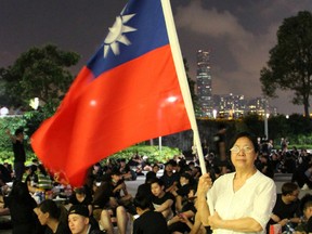 Protester Yung Xiu Kwan, 67, poses for picture with a Taiwan flag during a demonstration against the proposed extradition bill, in Hong Kong, China June 17, 2019.