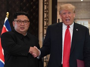 US President Donald Trump (R) and North Korea's leader Kim Jong Un shake hands following a signing ceremony during their historic US-North Korea summit, at the Capella Hotel on Sentosa island in Singapore.