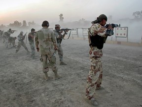 A U.S. Navy SEAL, (C), watches Iraqi army scouts train in 2007 in Fallujah, Iraq.