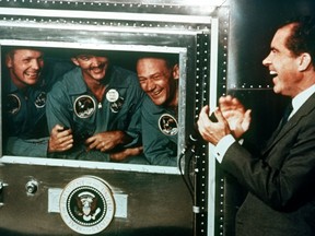 U,S, President Richard Nixon applauds the Apollo 11 astronauts, l-r, Neil Armstrong, Michael Collins and Buzz Aldrin who are confined in the quarantine trailer on July 25, 1969