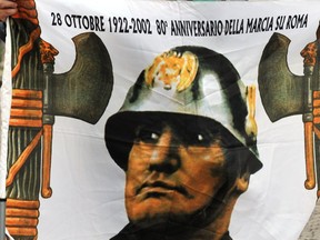 A man holds a banner with a portrait of Italian fascist dictator Benito Mussolini during a rally on October 28, 2012  in Predappio.