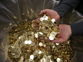 An employee holds a handful of blank coins at the Royal Canadian Mint Ltd. manufacturing facility in Winnipeg.