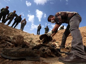 In this file photo taken on Feb. 03, 2015, members of the Yezidi minority search for clues that might lead them to missing relatives in the remains of people killed by ISIL. The image was taken a day after Kurdish forces discovered a mass grave near the Iraqi village of Sinuni, in the northwestern Sinjar area.