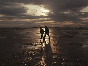 Toni Dawson, the wife of guide Brian Dawson, and Bill Booth, The Washington Post's London bureau chief, head back before the tide comes in along the Broomway path in England.