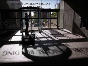 A City of Calgary employee cleans the glass of an entranceway at city hall in Calgary, Alta., on June 20, 2014. The City of Calgary has laid 65 fire code charges against a fire protection company and 10 of its employees.