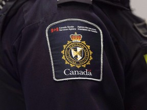 A Canadian Border Services agent stands watch at Pearson International Airport in Toronto on Tuesday, December 8, 2015. A group of doctors, lawyers, legal scholars and human rights organizations is calling on the federal government to halt the rollout of a new policy that will see border officers outfitted in defensive gear when dealing with refugees in detention.