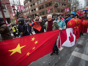 People carry Chinese and Canadian flags while marching in the Chinese New Year Parade in Vancouver on Sunday, Feb. 10, 2019. Some of the federal government's top bureaucrats have been warned about countries China and India trying to use their respective ethnic communities in Canada to advance their own agendas.