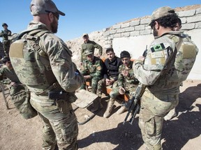 Canadian special forces soldiers, left and right, speak with Kurdish Peshmerga fighters at an observation post, in northern Iraq.Analysts say the escalating tensions in the Persian Gulf between Iran and the United States have implications for the future safety of Canadian troops in Iraq.