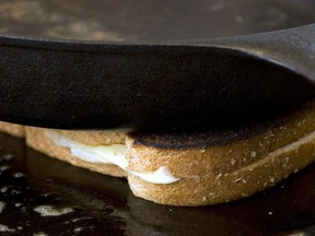 A cast iron pan is used to weigh down a grilled cheese sandwich as it cooks on a skillet on July 31, 2007.