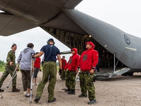 Canadian Armed Forces members help load evacuees on to a plane as smoke from a forest fire fills the sky near Pikangikum First Nation, Ont. in this undated handout photo. Residents of a First Nation threatened by a growing forest fire in northwestern Ontario began arriving in Regina on Thursday after the Saskatchewan government offered to host the evacuees.