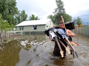 Resident Lars Androsoff carries his friend's guitars as he walks through the floodwaters in Grand Forks, B.C., on Thursday, May 17, 2018.