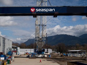 A worker walks through the Seaspan Vancouver Shipyards as the main girder of a new 300-tonne gantry crane is lifted into place in North Vancouver, B.C., on Wednesday April 2, 2014. New documents show a Vancouver shipyard was only able to deliver the first of the coast guard's three new science vessels guard last week by cannibalizing parts from one of the other ships for repairs.