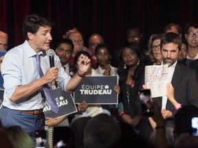 Prime Minister Justin Trudeau, left, addresses a protester during an event in Montreal, Wednesday, July 10, 2019, where Steven Guilbeault, right, launched his candidacy to run in the upcoming federal election for the Liberal party of Canada in the Montreal riding of Laurier-Sainte-Marie.