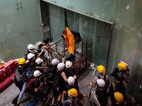Demonstrators ram a metal cart into a glass door at the Legislative Council building during a protest in Hong Kong, China, on Monday, July 1, 2019.