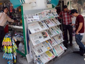 Iranian men use their mobile telephones in front of a newspaper stand in the capital Tehran on July 8, 2019.