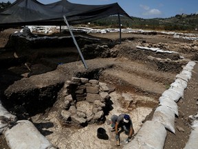 A man works next to a burial place at an excavation site where a huge prehistoric settlement was discovered by Israeli archaeologists in the town of Motza near Jerusalem July 16, 2019.