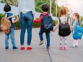 Mother and pupil and kids holding hands going to school in first class with schoolbag or satchel walking to school bus, Parent and son,sister preschool