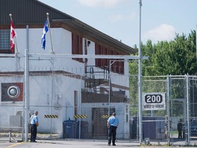 Guards stand outside the gates of an immigrant holding centre in Laval, Que., Monday, August 15, 2016.