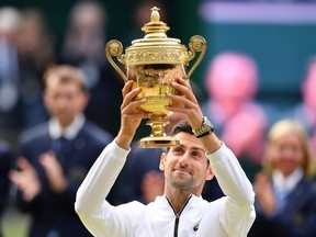 Serbia's Novak Djokovic raises the winner's trophy after beating Switzerland's Roger Federer during their men's singles final at the 2019 Wimbledon Championships on July 14, 2019.