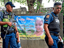 Police officers walk past a banner during a wake for three-year-old Kateleen Myca Ulpina, who was killed during a police sting operation, in Rodriguez, east of Manila, on July 7, 2019.