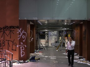 A member of staff walks past graffiti covered walls during a media tour inside Legislative Council building in Hong Kong, China, on Wednesday, July 3, 2019. Protesters occupied and ransacked Hong Kong's legislative chamber on Monday in a dramatic escalation of demonstrations against the city's China-appointed government.
