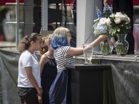 Family members and friends of the late Julianna Kozis, place a bouquet of flowers on the stage during a a commemoration of the Danforth shooting from one year ago, at Withrow Park in Toronto on Sunday, July 21, 2019.