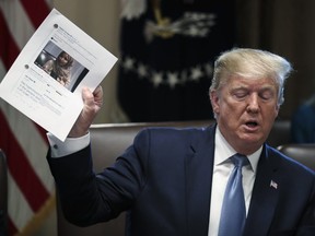 U.S. President Donald Trump holds up a piece of paper with an image of Representative Ilhan Omar, a Democrat from Minnesota, during a meeting in the Cabinet Room of the White House in Washington, D.C., U.S., on Tuesday, July 16, 2019.