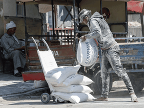 A Palestinian man piles bags of flour outside an aid distribution centre run by the United Nations Relief and Works Agency (UNRWA) in the central Gaza Strip refugee camp of Bureij, on July 31, 2019.