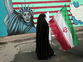 An Iranian woman holds her national flag as she walks past an anti-US mural depicting the Statue of Liberty on the wall of the former US embassy in Tehran on November 4, 2010 during a rally marking the 31st anniversary of the capture of the embassy by Islamist students.