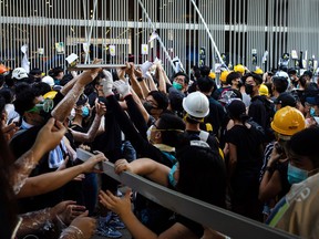 Demonstrators remove metal bars from a fence outside the Legislative Council building during a protest in Hong Kong, China, on Monday, July 1, 2019. Hong Kong's chief executive condemned protesters who occupied and ransacked the city's legislative chamber on Monday in an escalation of demonstrations against the China-appointed government, prompting police to fire tear gas to clear the area.