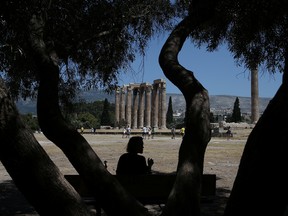 A tourist sits under the shadow of a tree during a hot day, at the archaeological site of the Temple of Zeus in Athens, Greece July 4, 2019.