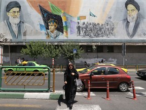 An Iranian woman walks past a mural depicting the late founder of the Islamic Revolution, Ayatollah Ruhollah Khomeini, right, and  Iran's supreme leader Ayatollah Ali Khamenei, in the Iranian capital, Tehran, on June 25, 2019.